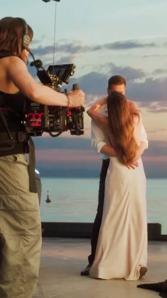 Camera filming a bride during a production at sunset.